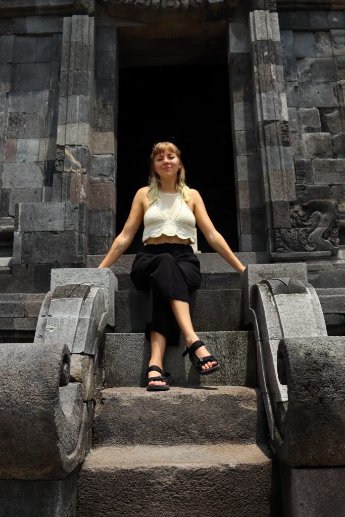 Ich sitze auf den Stufen eines Schreins am Prambanan Tempel bei Yogyakarta in Indonesien.