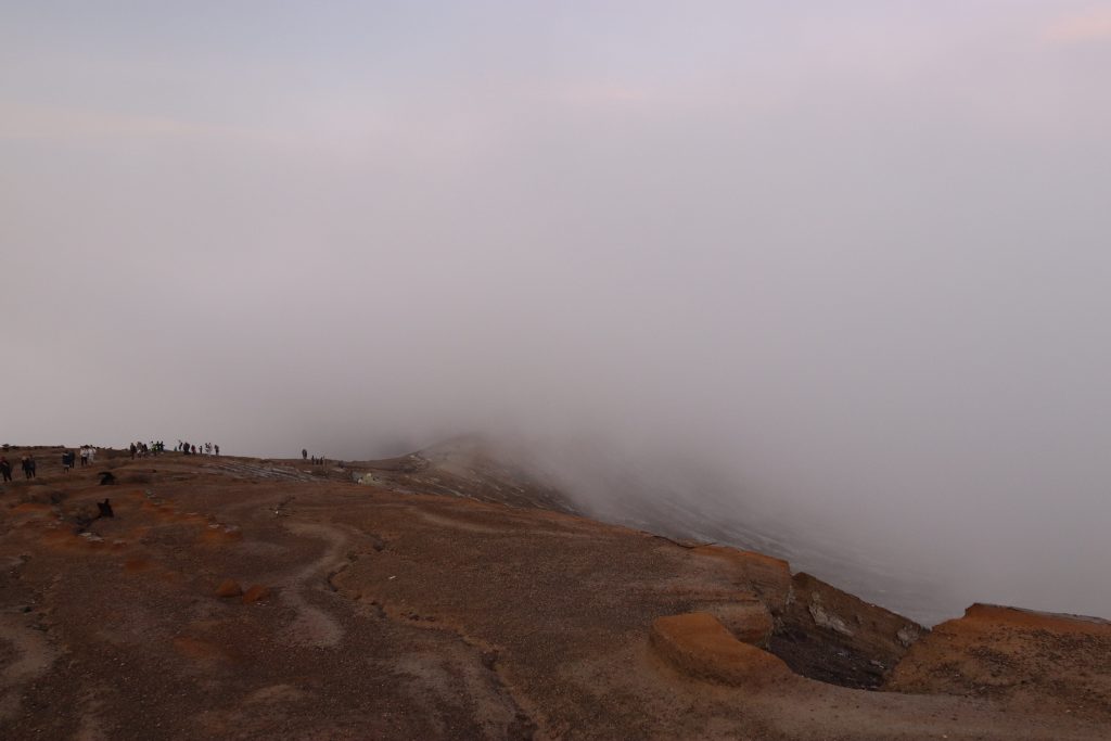 Krater des Ijen Vulkans bei Sonnenaufgang mit Schwefeldampf